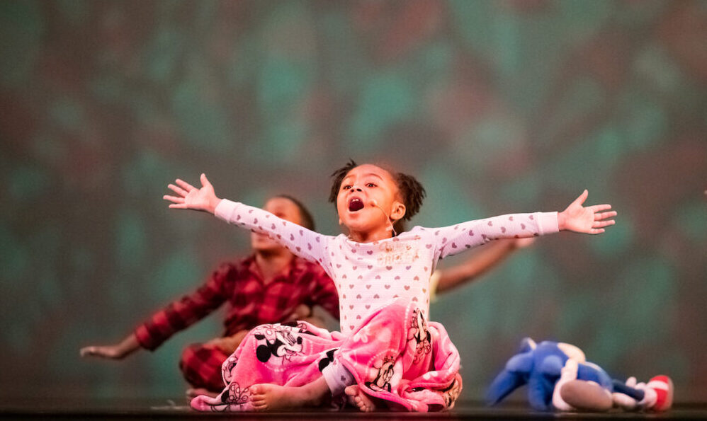 little girl on stage with her arms open